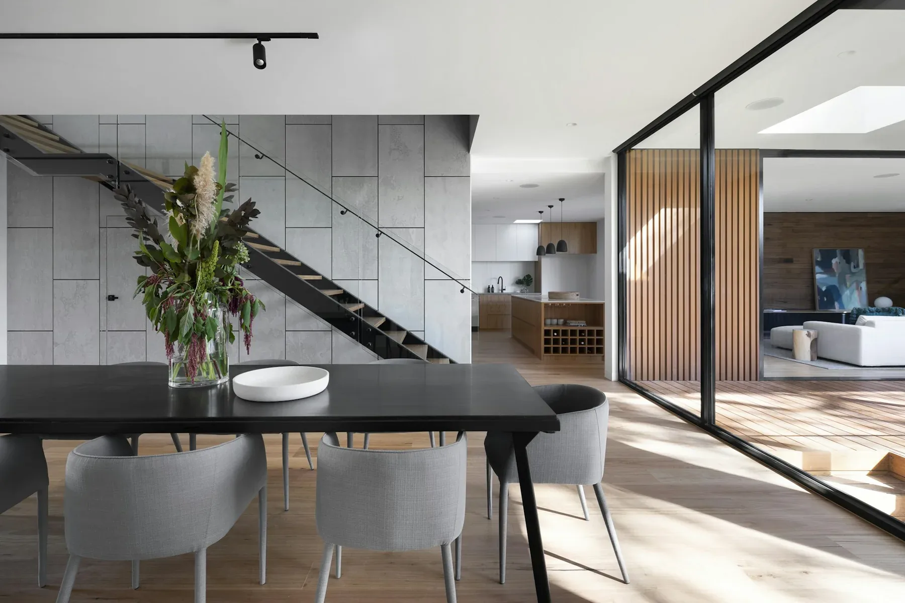 Contemporary dining space with concrete walls, timber screening and garden views