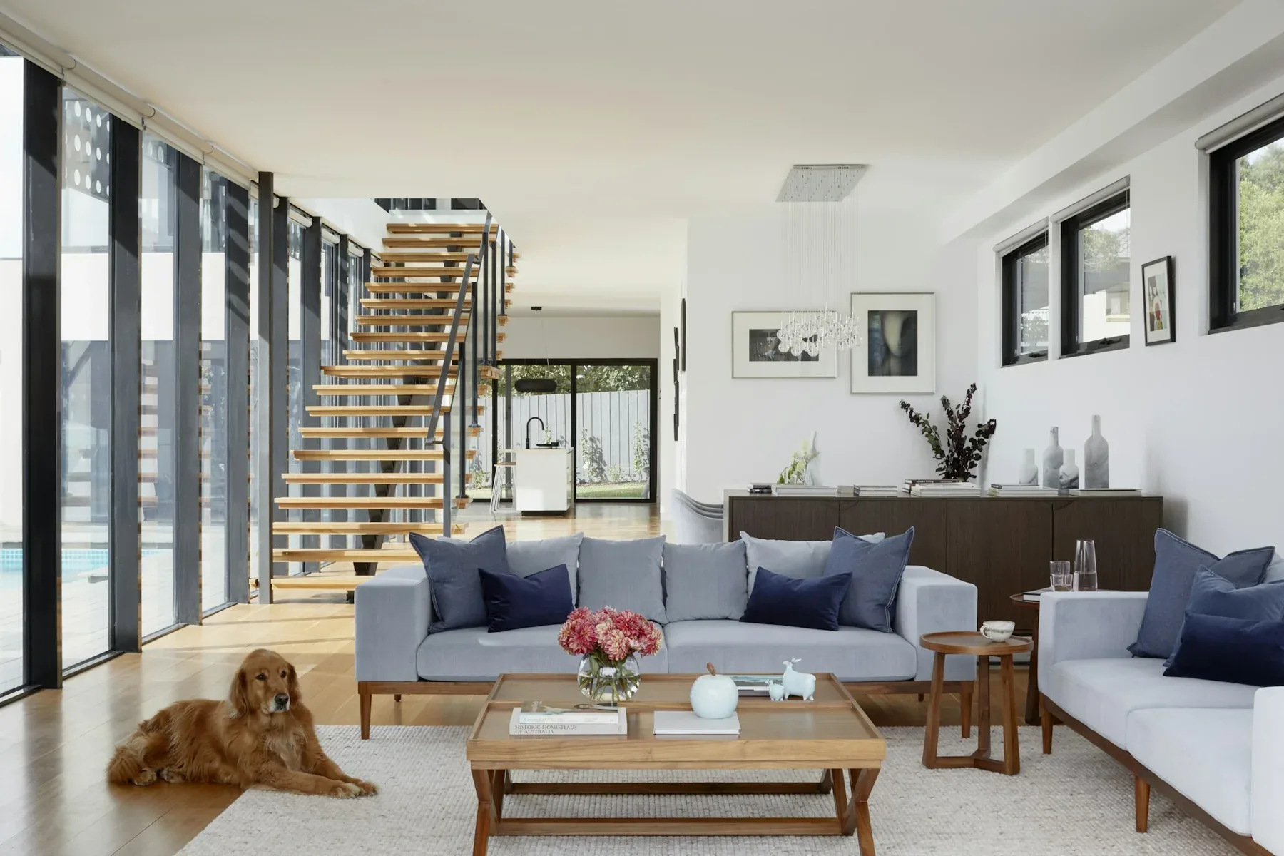 Airy living room with a timber stair screen, neutral seating and a natural-wood coffee table